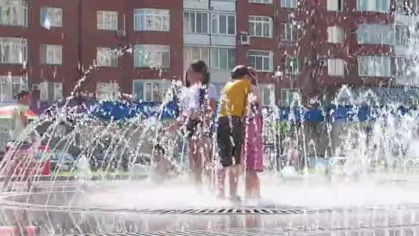 Novokuznetsk, Kemerovo region, Oroszország-június 28, 2019: boldog tizenévesek fröccsenő a víz egy városi szökőkút és élvezi a hűvös patakok a víz egy forró napon. — Stock videók
