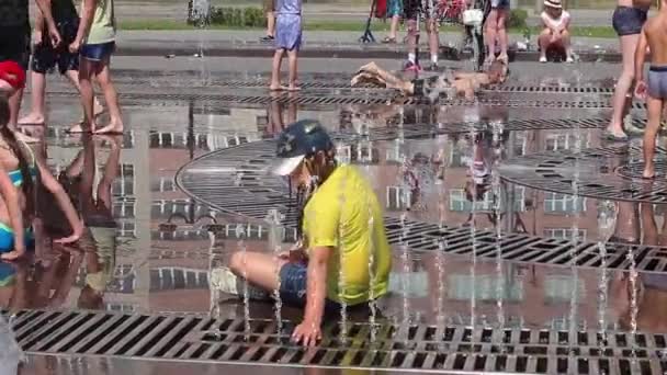 Novokuznetsk, région de Kemerovo, Russie - 28 juin 2019 : Des adolescents heureux éclaboussent dans l'eau d'une fontaine de la ville et profitent des flux d'eau frais lors d'une journée chaude . — Video