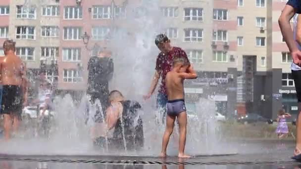 Novokuznetsk, Region Kemerowo, Russland - 28. Juni 2019: fröhliche Teenager planschen im Wasser eines Stadtbrunnens und genießen die kühlen Wasserströme an einem heißen Tag. — Stockvideo