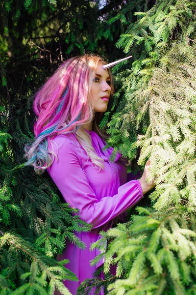 Fairy girl unicorn with pink hair in summer forest