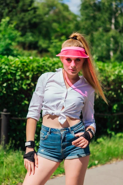 Retrato de una chica emocional con una visera de gorra rosa y guantes protectores para patines y skateboarding . — Foto de Stock