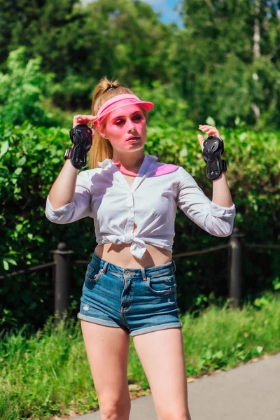 Portré egy érzelmi lány egy rózsaszín sapka Visor és védő kesztyű görkorcsolyák és gördeszka. — Stock Fotó