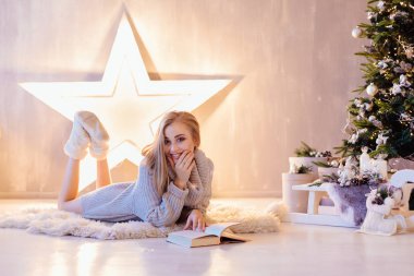 Döşeme ve bir tatil iç Noel ağacı altında kitap okuma güzel genç kadın