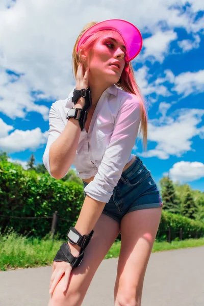 Retrato de una chica emocional con una visera de gorra rosa y guantes protectores para patines y skateboarding . — Foto de Stock