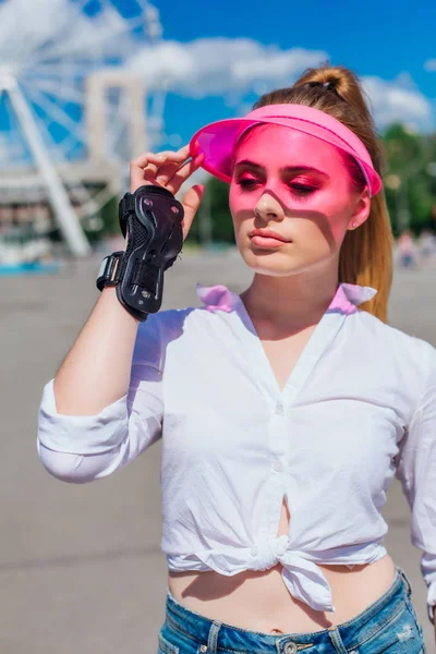 Retrato de uma menina emocional em uma viseira de boné rosa e luvas de proteção para patins e skate . — Fotografia de Stock