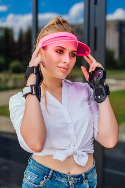 Porträtt av en känslomässig flicka i en rosa mössa visir och skyddshandskar för rullskridskor och skateboard. — Stockfoto