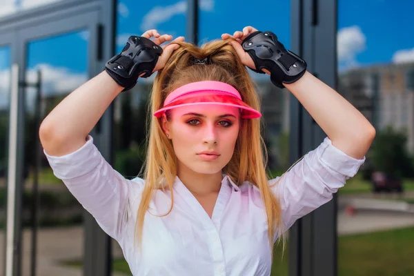Retrato de uma menina emocional em uma viseira de boné rosa e luvas de proteção para patins e skate . — Fotografia de Stock
