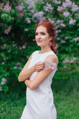 Lila Bush yanında güzel beyaz elbise ayakta giyen büyüleyici kadın