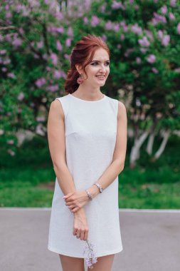 Lila Bush yanında güzel beyaz elbise ayakta giyen büyüleyici kadın