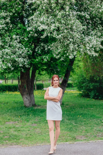 Charmante vrouw het dragen van mooie witte jurk onder de appelboom — Stockfoto