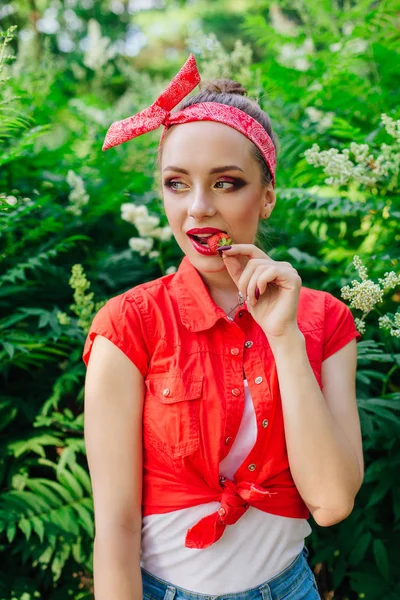 Schöne junge Pin-up-Mädchen mit hellem Make-up essen frische natürliche Erdbeere. — Stockfoto