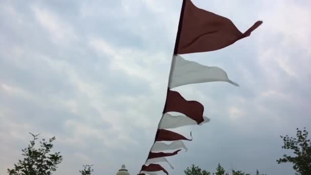 Bruna och vita triangel flaggor på vinden. — Stockvideo