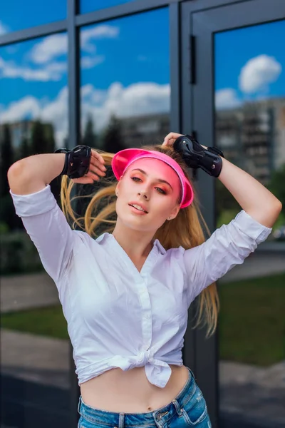 Porträtt av en känslomässig flicka i en rosa mössa visir och skyddshandskar för rullskridskor och skateboard. — Stockfoto