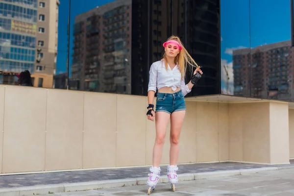 Portret emocjonalnej dziewczyny w różowym daszkiem i rękawice ochronne do rolek i skateboardingu jazda na rolkach na drodze. — Zdjęcie stockowe