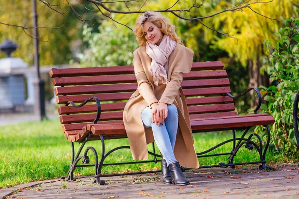 Sonbahar parkında bankta oturan genç güzel kadın