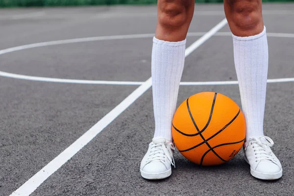 白いスニーカーでウォナンの足を閉じ、バスケットボールコートでボールを持つ長い靴下を締めくくる. — ストック写真