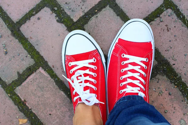 Red sneakers shoes on woman's and man's feet.