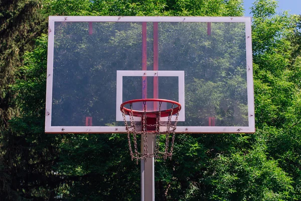 Outdoor basketball ring in front of green trees background. — Stock Photo, Image