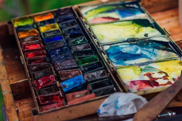 Palette of watercolor paints and brushes on the wooden background. — Stock Photo, Image