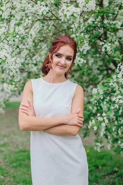 Mujer encantadora vistiendo hermoso vestido blanco bajo el manzano — Foto de Stock