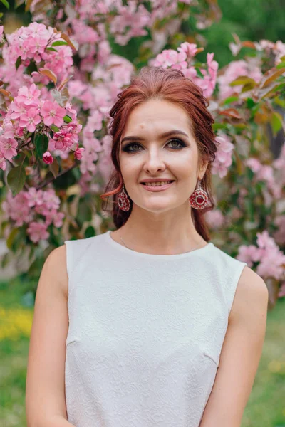 Charmante Frau in schönem weißen Kleid steht neben dem rosa Apfelbaum — Stockfoto