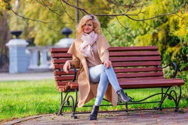 Sonbahar parkında bankta oturan genç güzel kadın