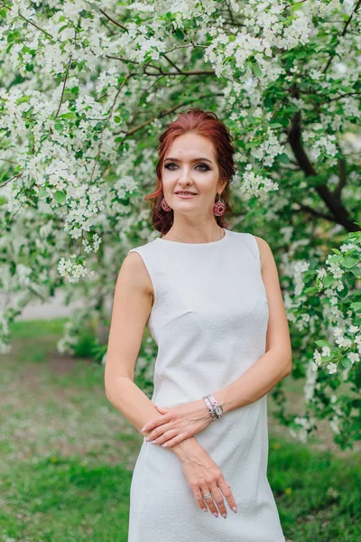 Charmante Frau in schönem weißen Kleid unter dem Apfelbaum — Stockfoto