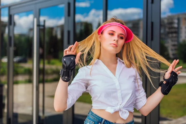 Retrato de uma menina emocional em uma viseira de boné rosa e luvas de proteção para patins e skate . — Fotografia de Stock