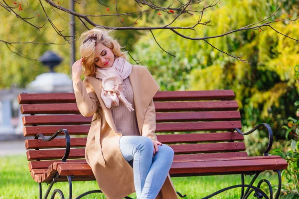 Młoda piękna kobieta siedzi na ławce w jesiennym parku — Zdjęcie stockowe