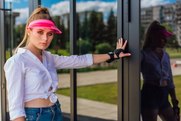 Retrato de una chica emocional con una visera de gorra rosa y guantes protectores para patines y skateboarding . —  Fotos de Stock