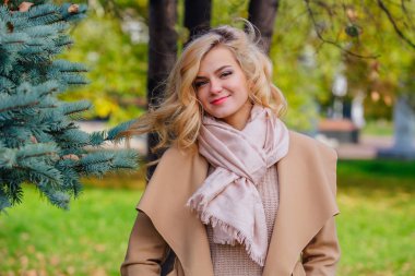 Sonbahar parkında köknar ağacının altında duran güzel zarif kadın