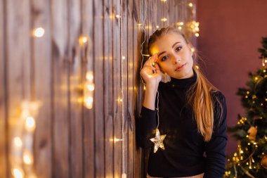 Yıldız ve ay ışıkları ile ahşap duvarın yanında duran bir kazak ve etek giymiş güzel genç kadın