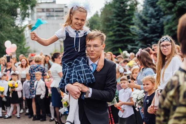 NOVOKUZNETSK, KEMEROVO REGION, RUSSIA - SEP, 1, 2018: September first-the day of knowledge in Russia. Meeting with the first-grade pupils and teacher at schoolyard — Stock Photo, Image