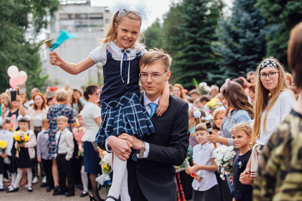 NOVOKUZNETSK, KEMEROVO REGION, RUSSIA - SEP, 1, 2018: September first-the day of knowledge in Russia. Meeting with the first-grade pupils and teacher at schoolyard