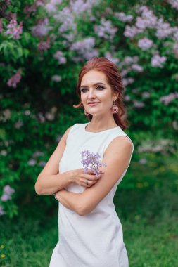 Lila Bush yanında güzel beyaz elbise ayakta giyen büyüleyici kadın