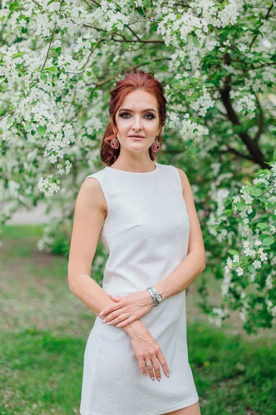 Mulher encantadora vestindo belo vestido branco sob a árvore da maçã — Fotografia de Stock