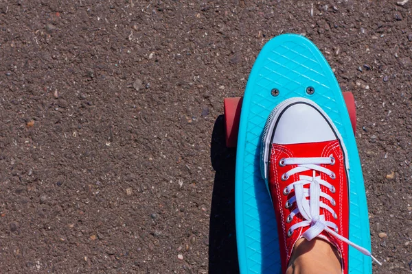 Nahaufnahme von Füßen und blauem Penny-Skateboard mit rosa Rädern. — Stockfoto