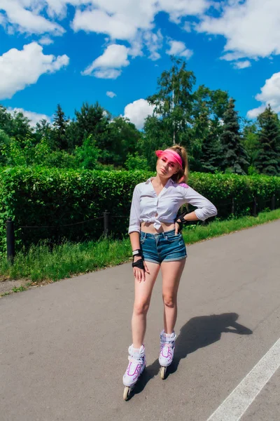 Portret van een emotioneel meisje in een roze GLB Visor en beschermende handschoenen voor inline skates en skateboarden rijden op inline skates op de weg. — Stockfoto