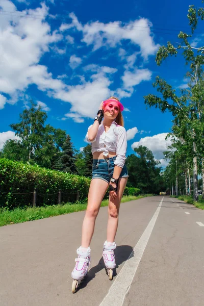 Retrato de una chica emocional en una visera de gorra rosa y guantes protectores para patines y patinetas montadas en patines en la carretera . —  Fotos de Stock