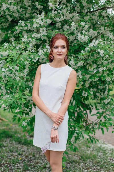 Urocza kobieta ubrana w piękną białą sukienkę stojącą pod jabłkiem — Zdjęcie stockowe