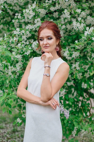 Charmante vrouw het dragen van mooie witte jurk staande onder de appelboom — Stockfoto