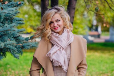 Sonbahar parkında köknar ağacının altında duran güzel zarif kadın