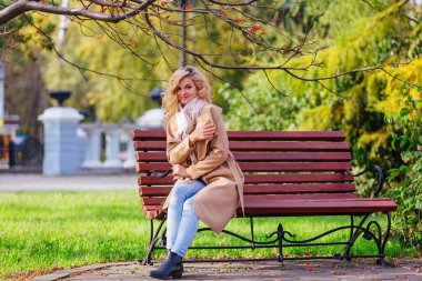 Sonbahar parkında bankta oturan genç güzel kadın