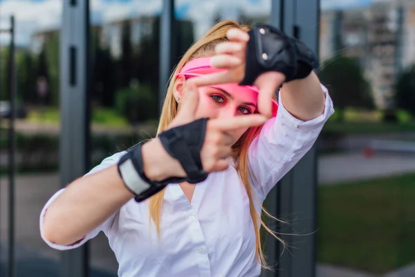 Ritratto di una ragazza emotiva con visiera a cappuccio rosa e guanti protettivi per pattini e skateboard . — Foto Stock