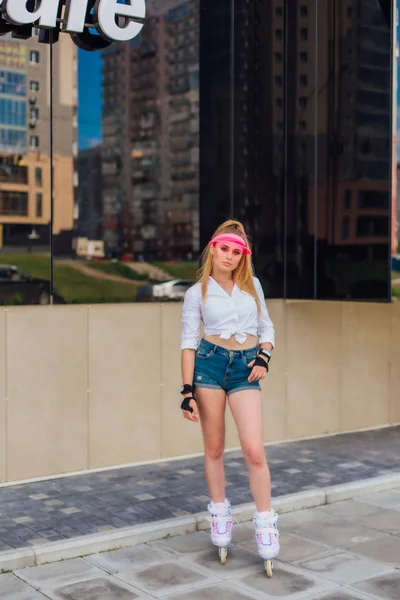 Retrato de una chica emocional en una visera de gorra rosa y guantes protectores para patines y patinetas montadas en patines en la carretera . —  Fotos de Stock