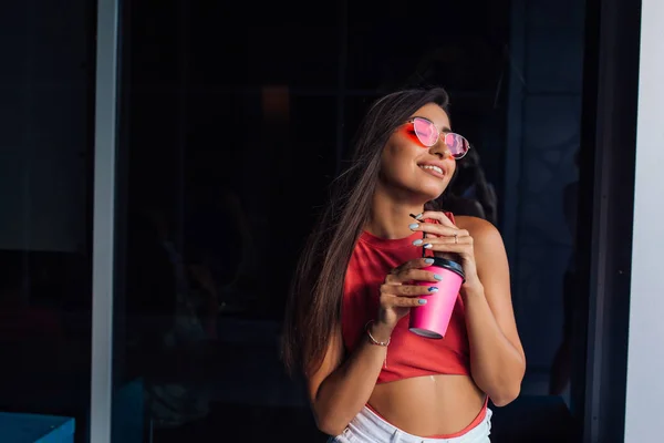 Elegante joven morena feliz sosteniendo una taza de café rosa para llevar . —  Fotos de Stock