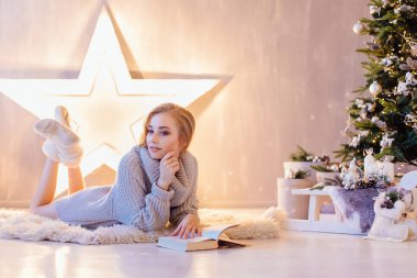 Döşeme ve bir tatil iç Noel ağacı altında kitap okuma güzel genç kadın