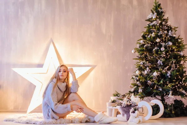 Hermosa joven posando bajo el árbol de Navidad en un interior de vacaciones —  Fotos de Stock