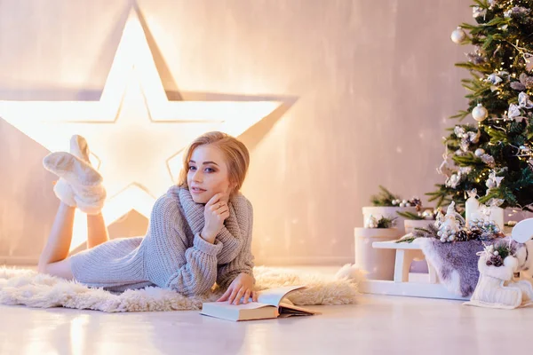 Döşeme ve bir tatil iç Noel ağacı altında kitap okuma güzel genç kadın