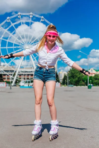 Retrato de una chica emocional en una visera de gorra rosa y guantes protectores para patines y patinetas montadas en patines en la carretera . —  Fotos de Stock